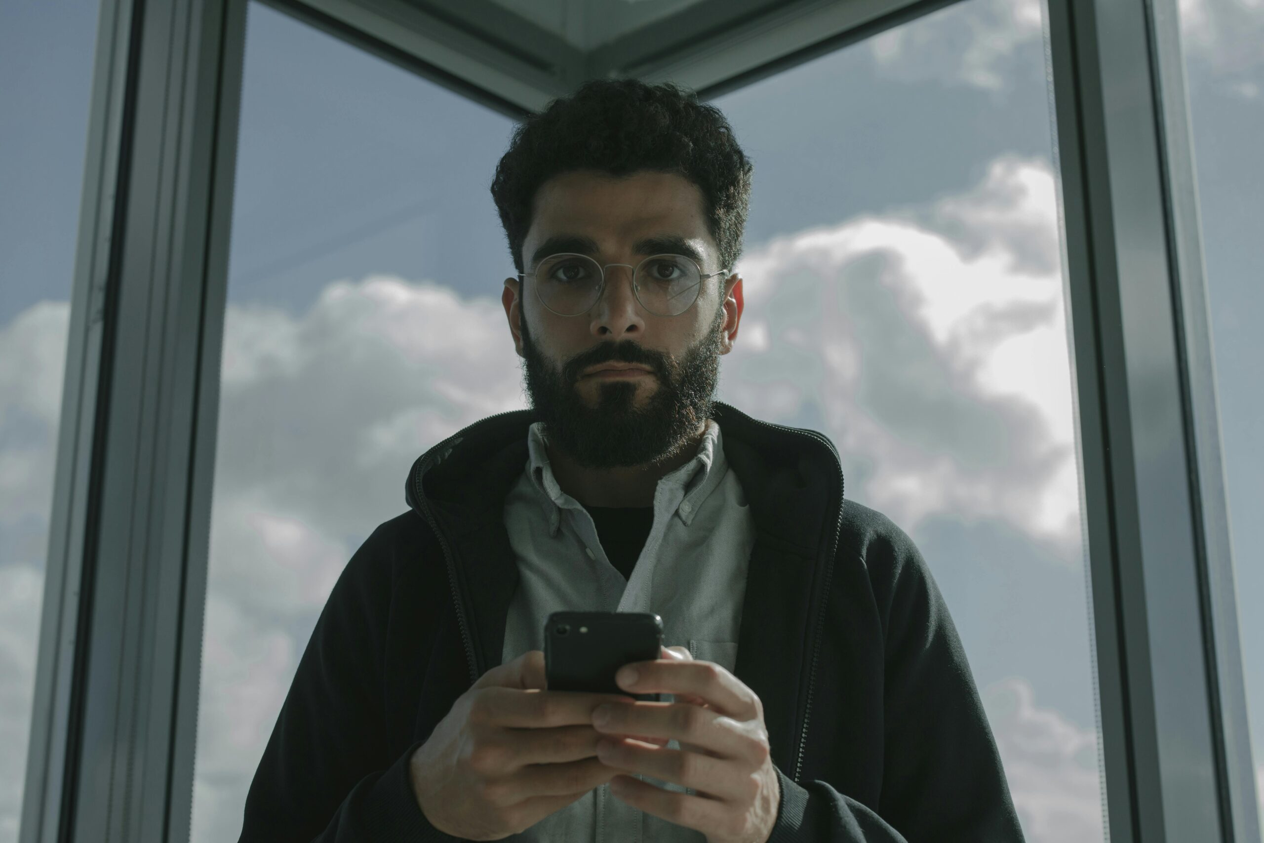 A Man in Black Jacket Holding a Smartphone