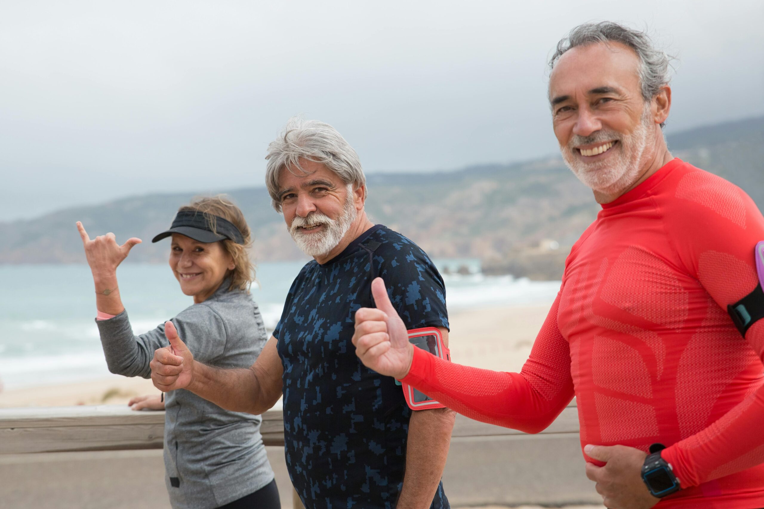 Smiling senior friends exercising on a beach in Portugal, embracing a healthy lifestyle.