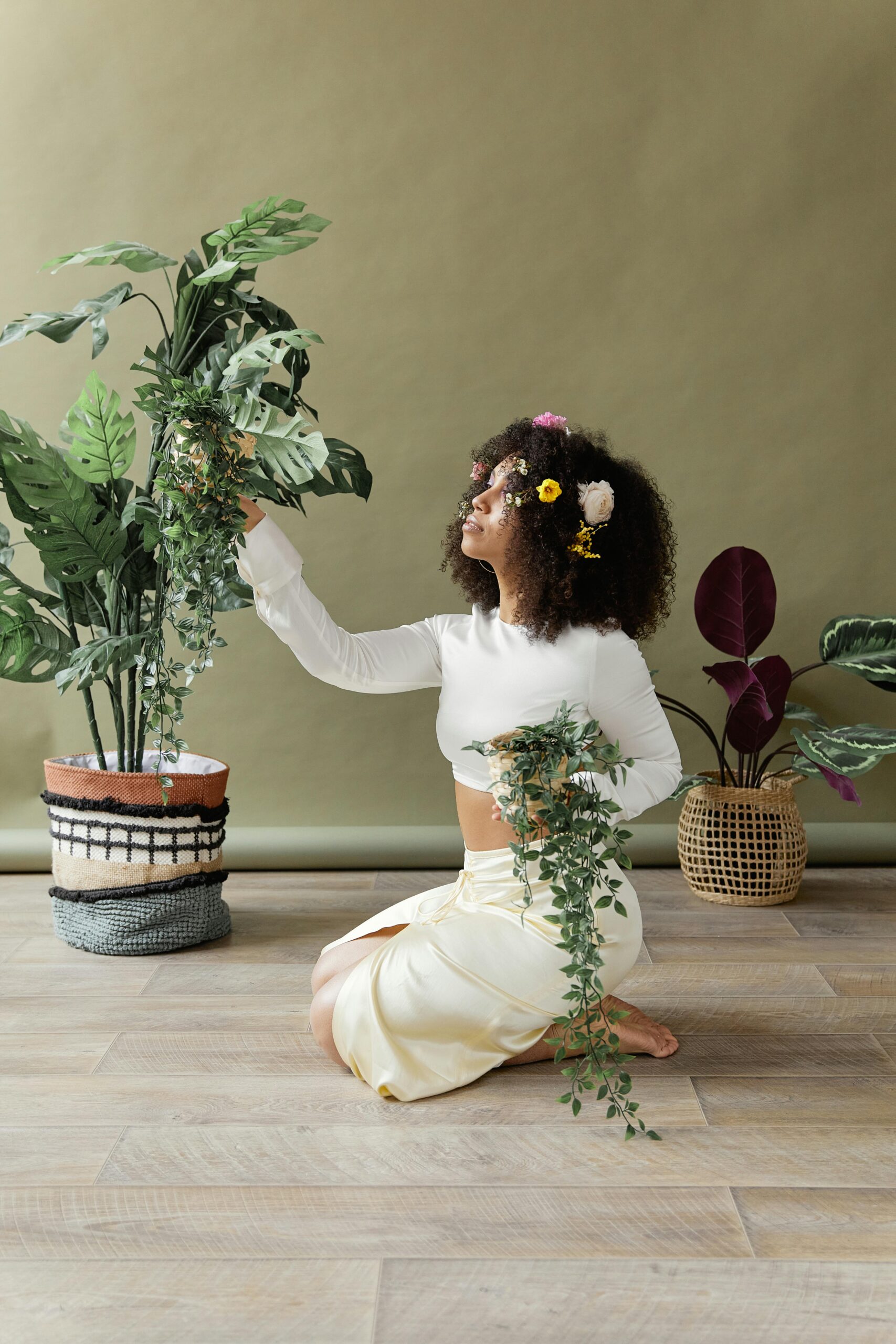 African American woman with afro hairstyle arranging plants indoors, exuding natural glamour.