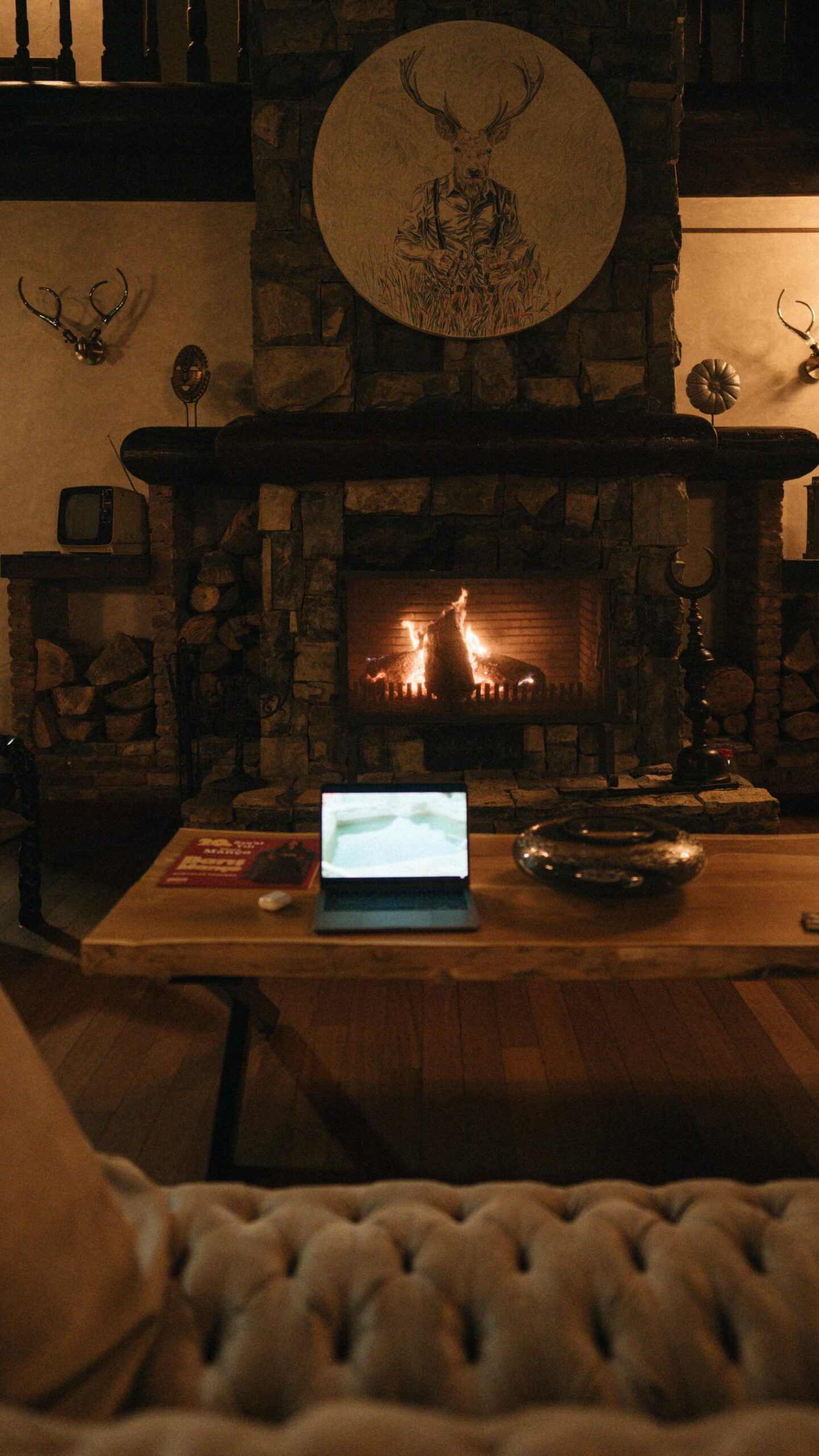 A warm living room with a fireplace and tablet on a wooden table.
