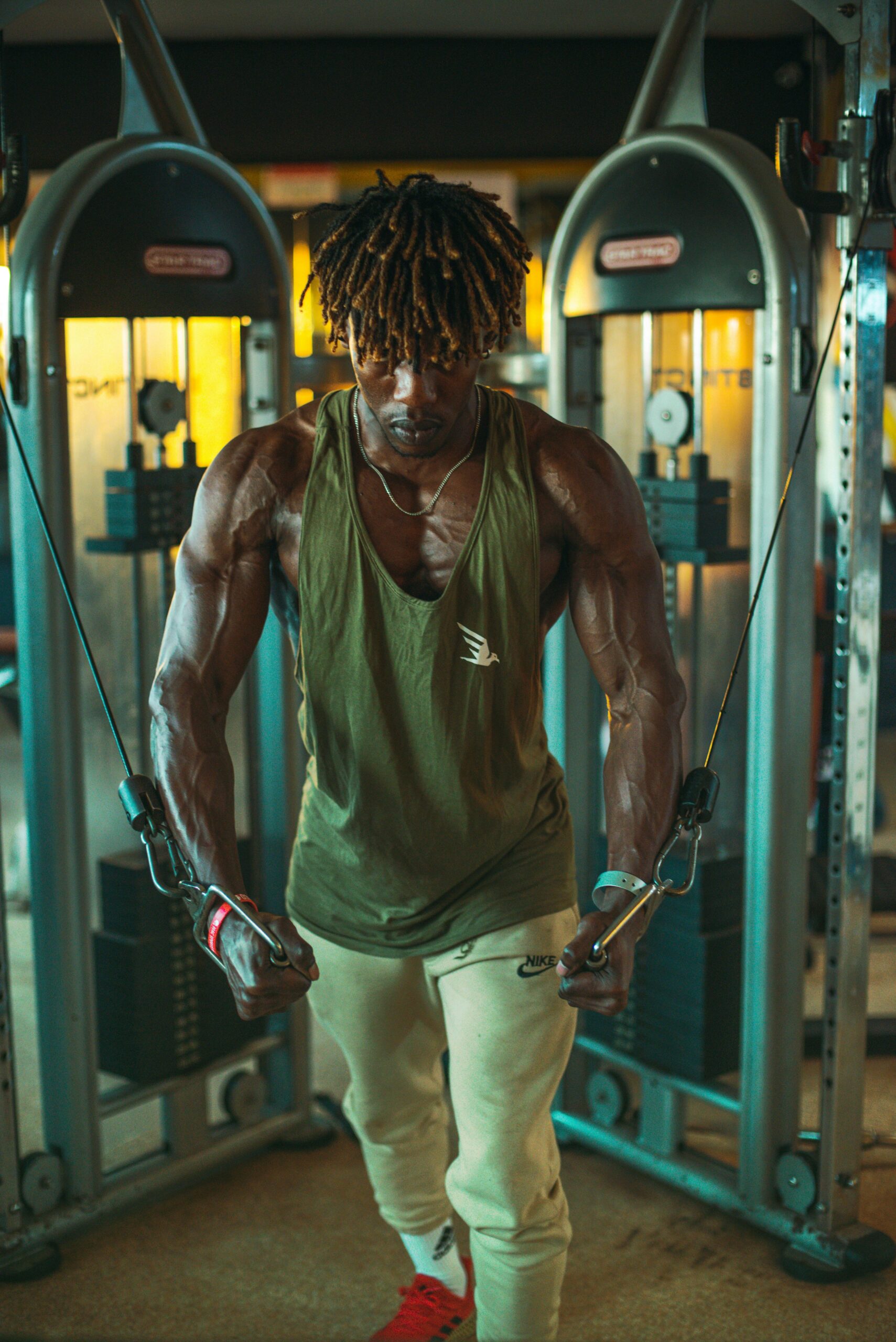 Muscular man performing cable exercises in a modern gym environment.
