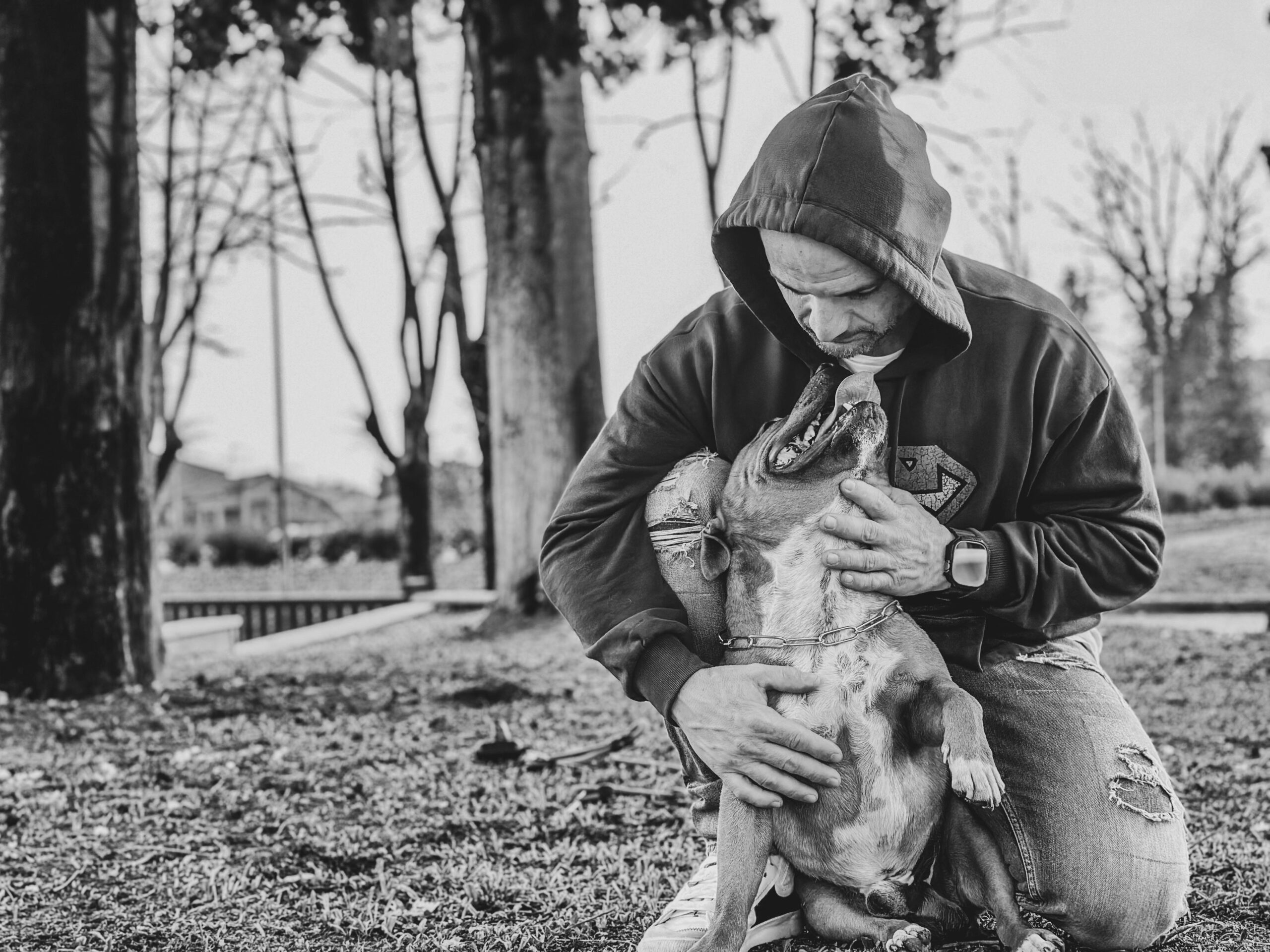 A heartfelt bond between a man and his dog in an outdoor setting. Black and white.
